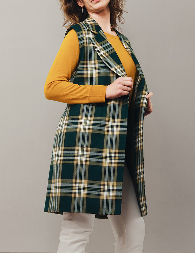 Modelo con abrigo de mujer sin mangas con dos bolsillos delanteros.