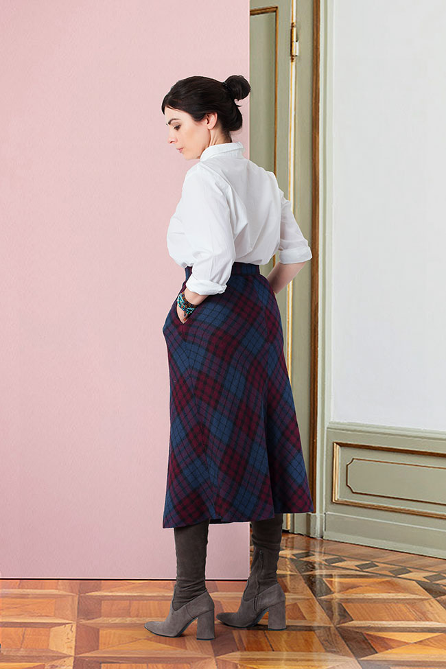 Modelo vistiendo falda largura midi estampada en cuadros de tartán escocés.