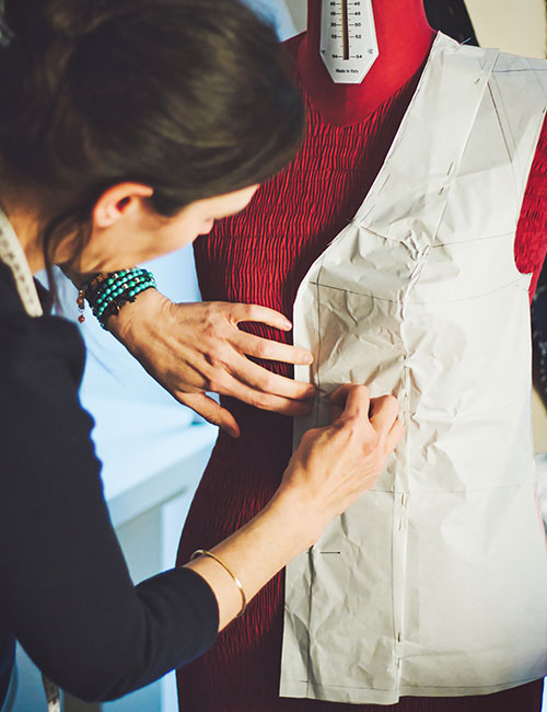 Mujer sastre ajustando patrón sobre el maniqui